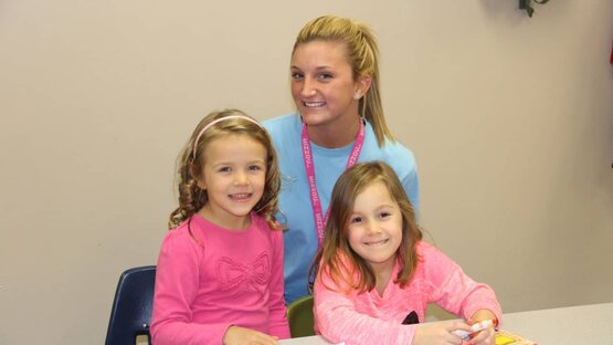 A teacher helping two of her students with their schoolwork.